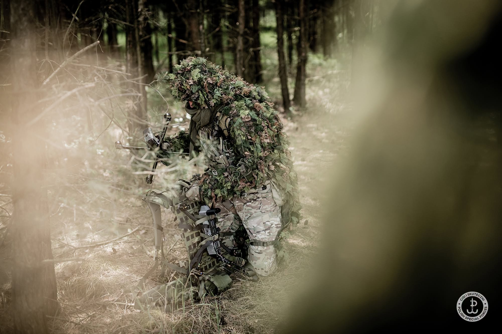 Komandos JWK w pełnym maskowaniu ghillie z dronem przenoszonym na racku plecaka