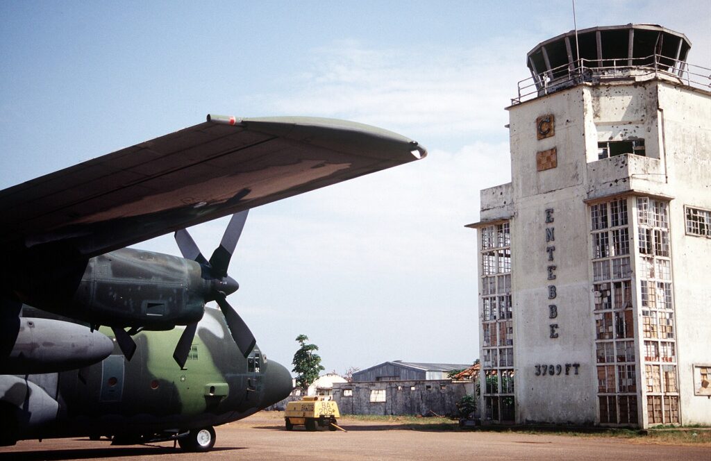 C-130 Hercules przed starym terminalem Entebbe - na elewacji wciąż ślady po kulach z 1976 r. (zdjęcie z 1994). Fot. Andy Dunaway / US DoD, domena publiczna