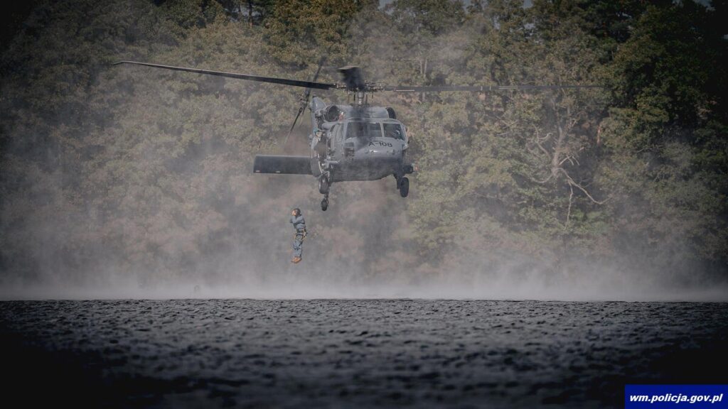 Kontrterrorysta skacze do wody z policyjnego śmigłowca S-70i Black Hawk, pod maszyną tuman wodnego pyłu