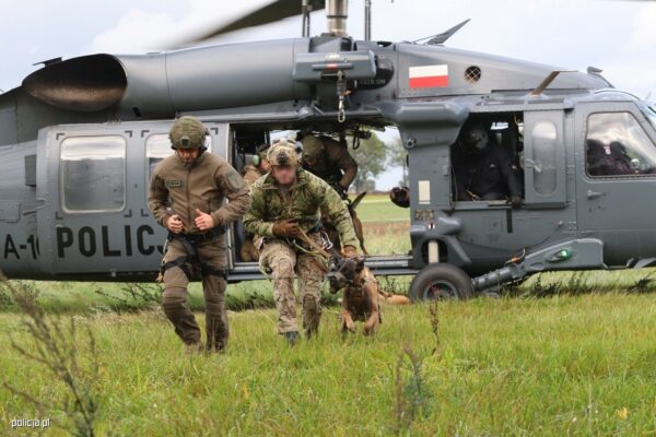 Policyjny kontrterrorysta z psem służbowym wysiada z policyjnego śmigłowca Black Hawk
