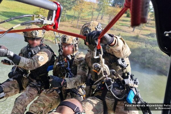Policyjni kontrterroryści zawieszeni na linach pod śmigłowcem S-70i Black Hawk nad zbiornikiem wodnym w Bieszczadach