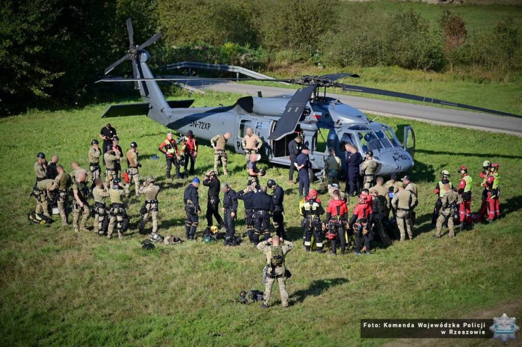 Śmigłowiec S-70i Black Hawk na górskiej polanie i uczestnicy ćwiczeń, widok z oddali