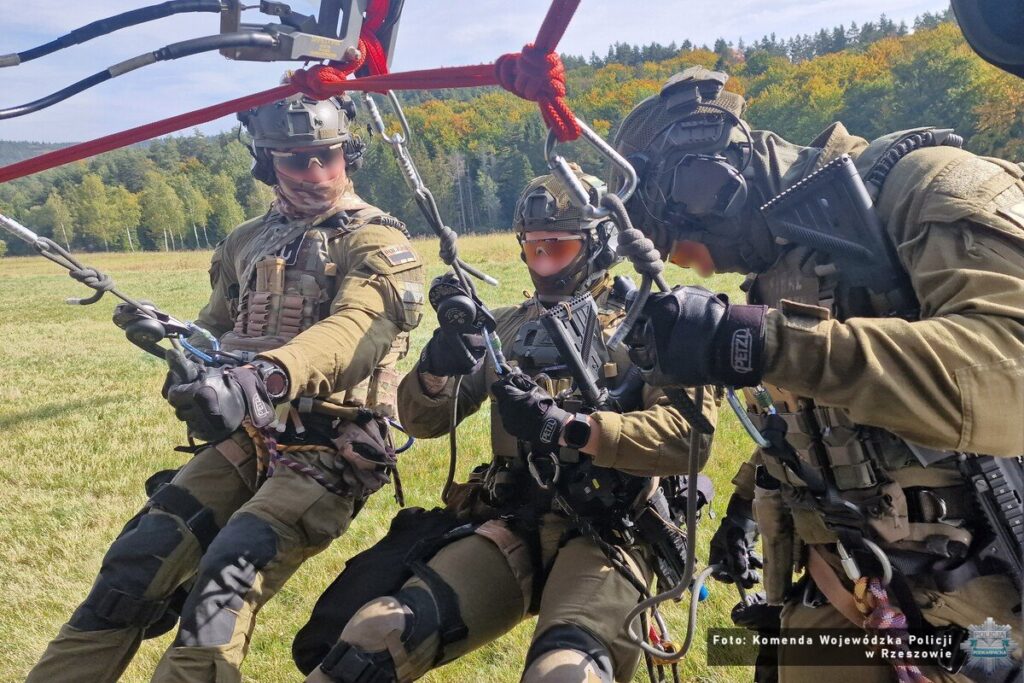 Zespół kontrterrorystów na linie pod śmigłowcem tuż nad łąką