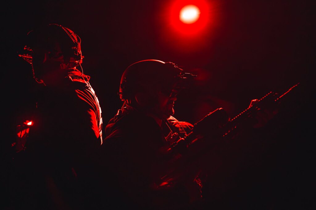 Operatorzy z bronią podczas nocnej próby sprzętu w czerwonym świetle