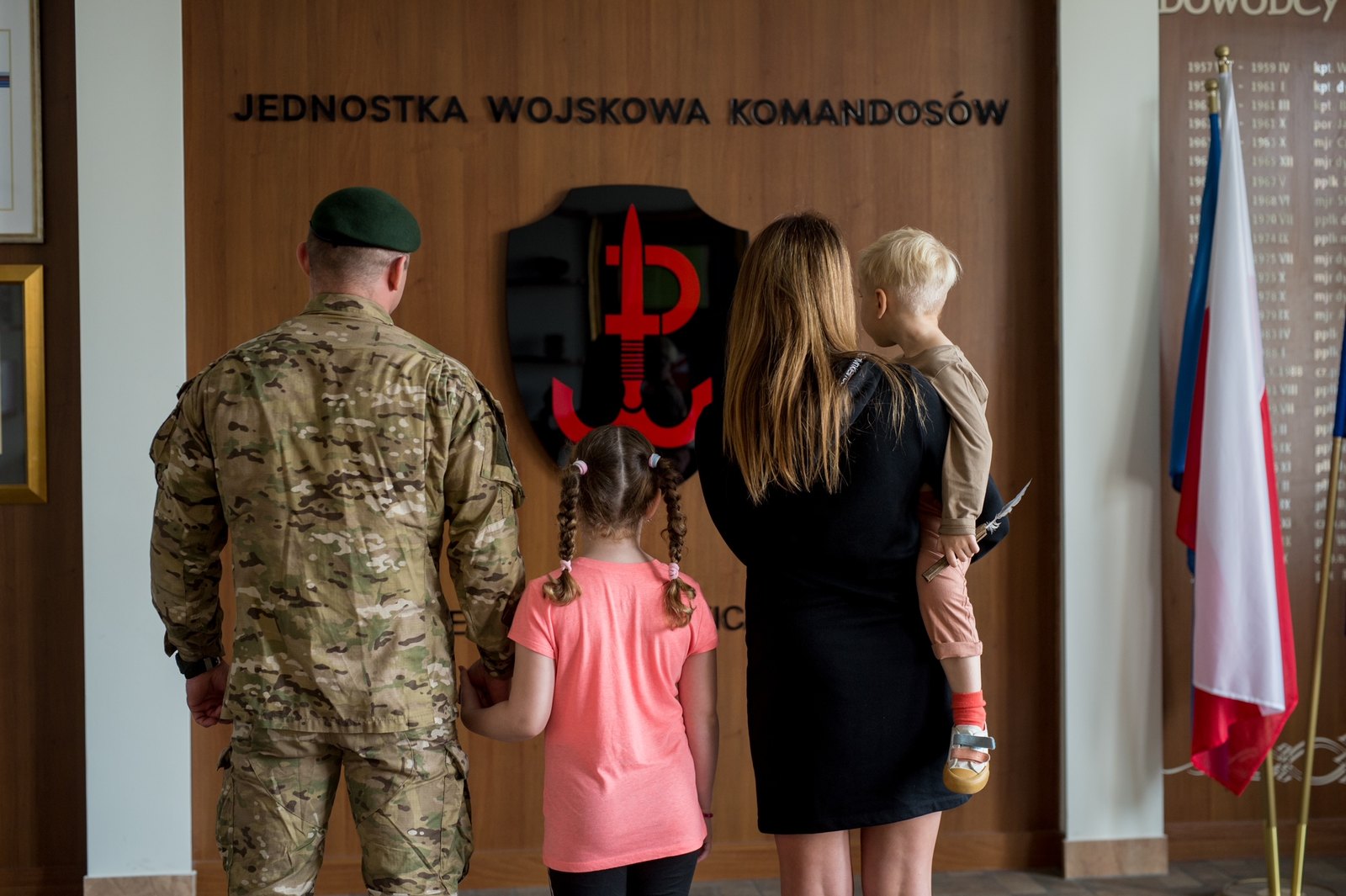 Żołnierz JWK z rodziną przed godłem Jednostki Wojskowej Komandosów w Lublińcu