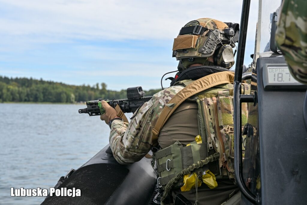 Operator z bronią gotową do strzału przy burcie płynącej łodzi
