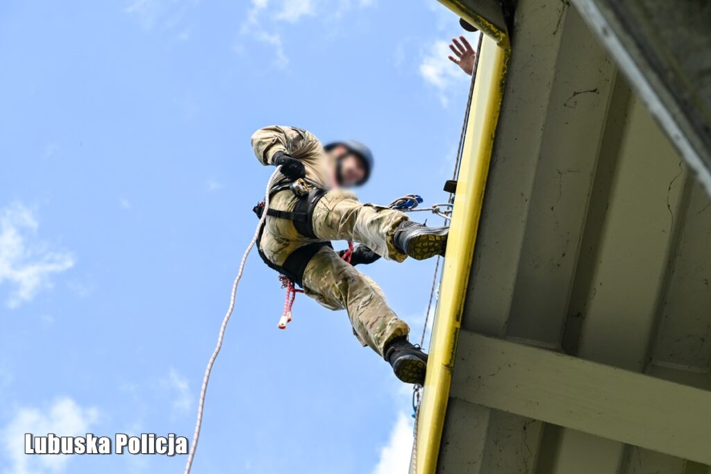 Operator podciąga się na krawędź stalowej konstrukcji podczas ćwiczeń wysokościowych
