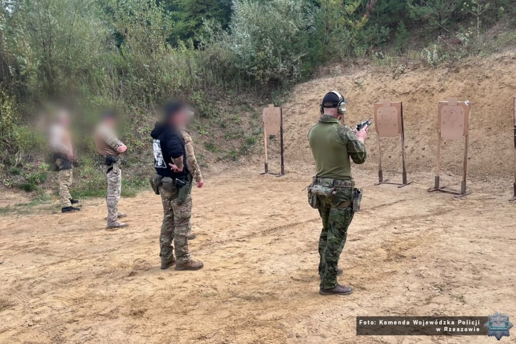 Instruktor obserwuje policyjnego kontrterrorystę strzelającego z pistoletu na strzelnicy w Maryninie